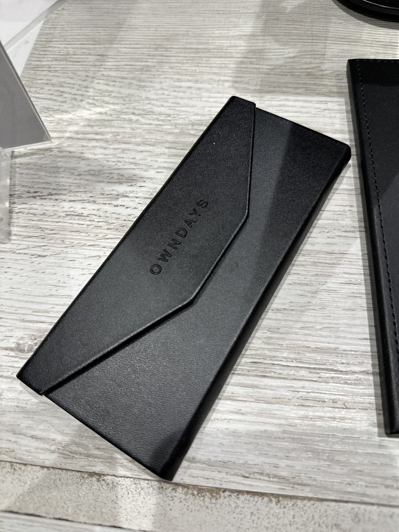 A sleek black OWNDAYS glasses case with the brand logo displayed on a wooden surface.