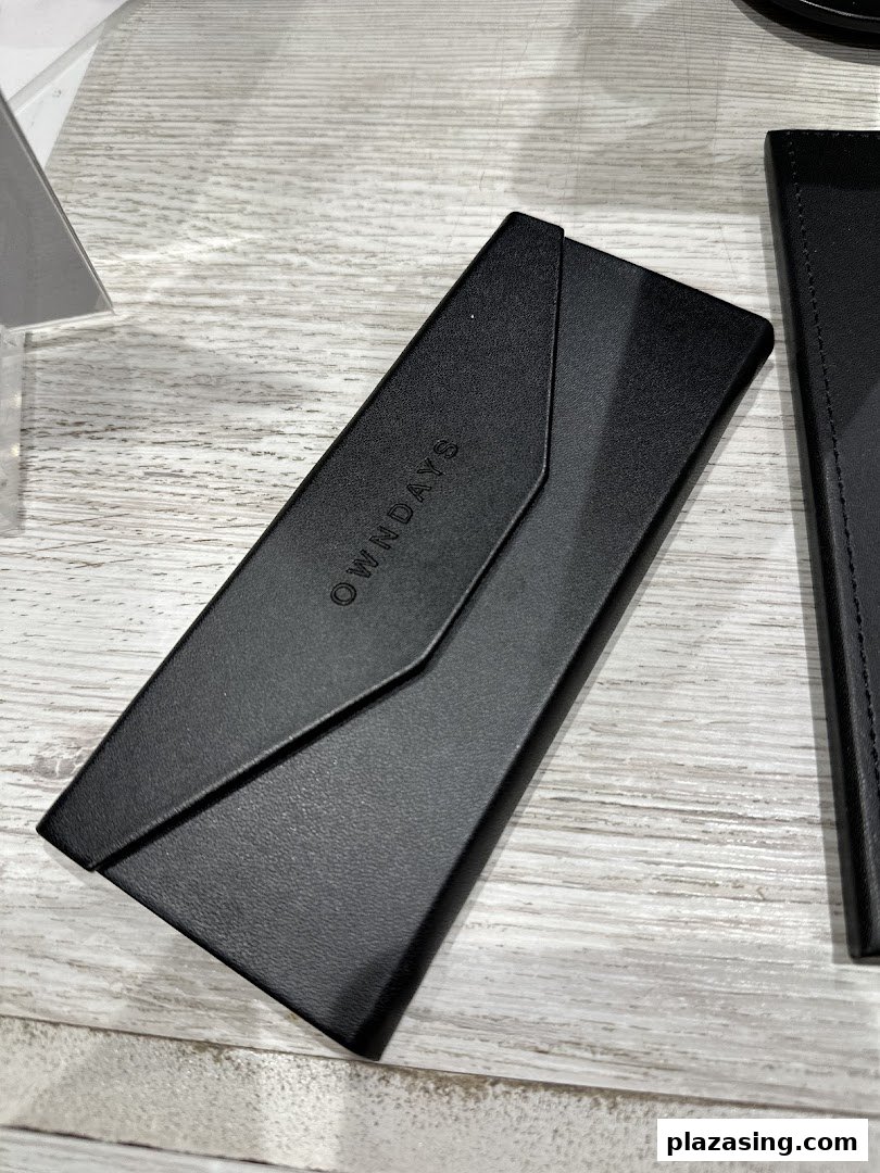 A sleek black OWNDAYS glasses case with the brand logo displayed on a wooden surface.