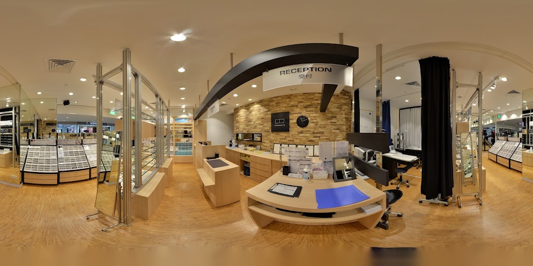 A panoramic view of OWNDAYS eyewear store interior, featuring the reception desk and extensive glasses displays.