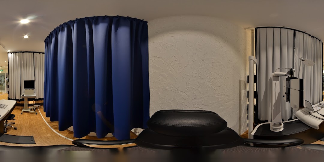Interior view of an OWNDAYS shop, featuring private consultation areas with blue and white curtains and optical equipment.
