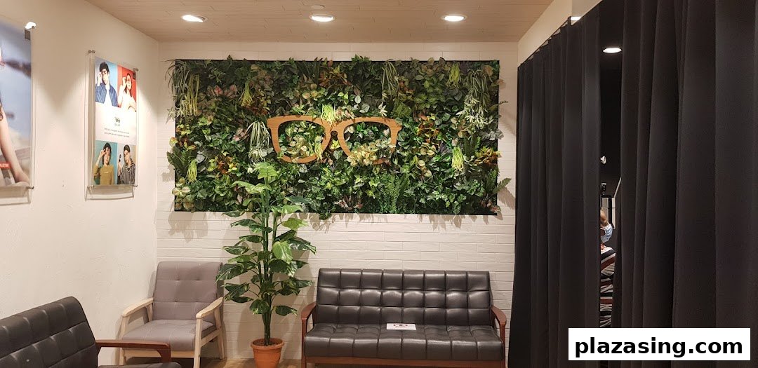 Interior view of OWNDAYS waiting area with green wall art featuring an eyeglasses motif and comfortable seating.