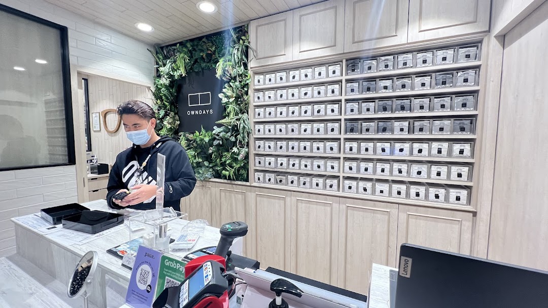 A staff member assists at the counter of OWNDAYS, surrounded by stylish eyewear displays.