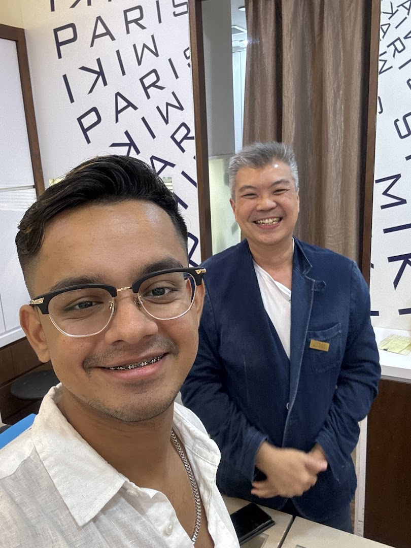 A happy customer wearing new glasses takes a selfie with a smiling staff member at Paris Miki.