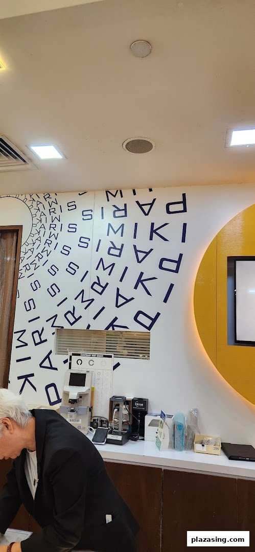 Interior view of Paris Miki optician, showing eye care equipment and a customer at the counter.