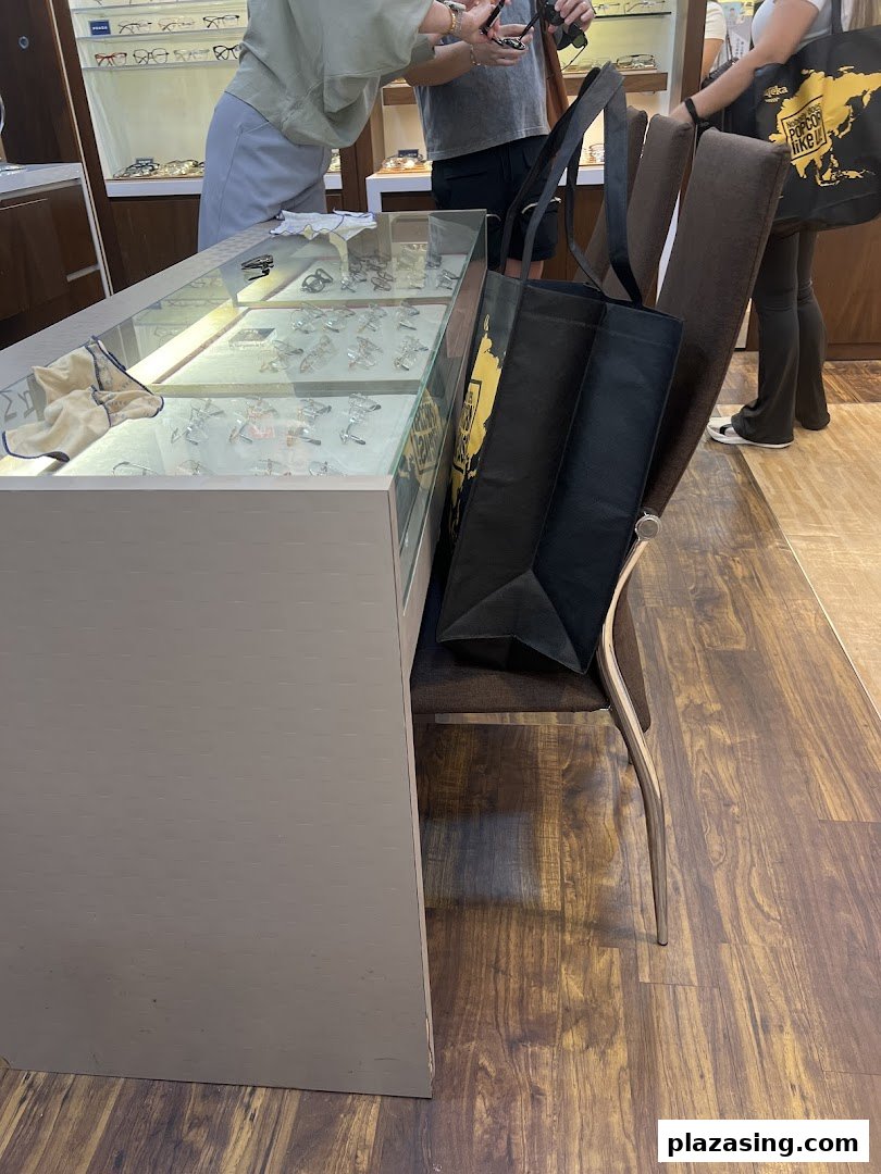 Customers browse eyewear in a well-lit display case at an optician's shop.