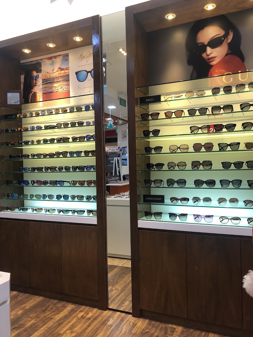 Brightly lit display cases showcase a wide selection of sunglasses from various brands like Gucci and Maui Jim.