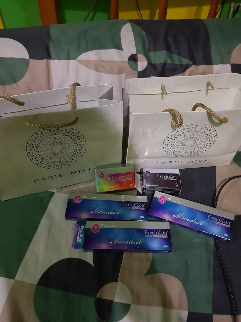 Contact lens boxes and shopping bags from Paris Miki, showcasing FreshKon products.