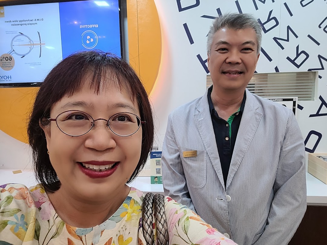 Two smiling individuals, likely a customer and staff, inside an optical shop.