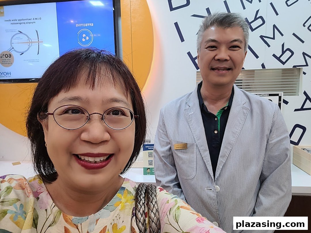Two smiling individuals, likely a customer and staff, inside an optical shop.