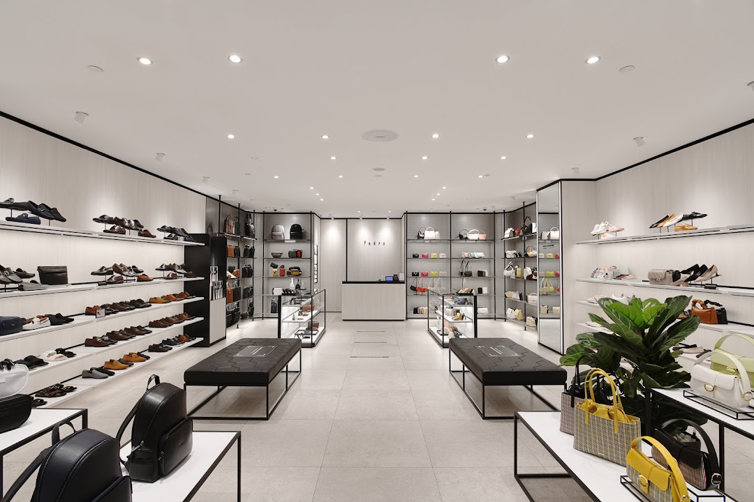 A brightly lit, modern retail interior of PEDRO, showcasing a wide array of shoes, bags, and accessories.