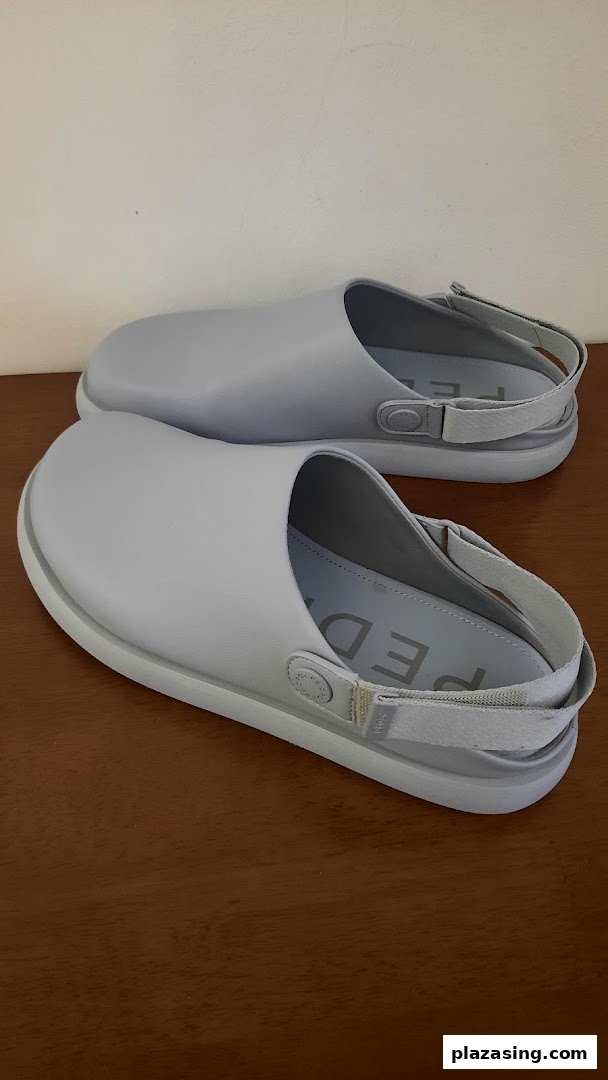 Two light grey, modern clogs with slingback straps are displayed on a wooden surface.