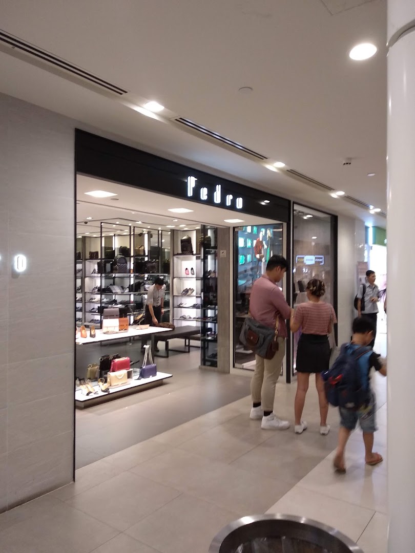 The illuminated entrance of PEDRO at Plaza Singapura, showcasing its modern interior with shoes and bags.