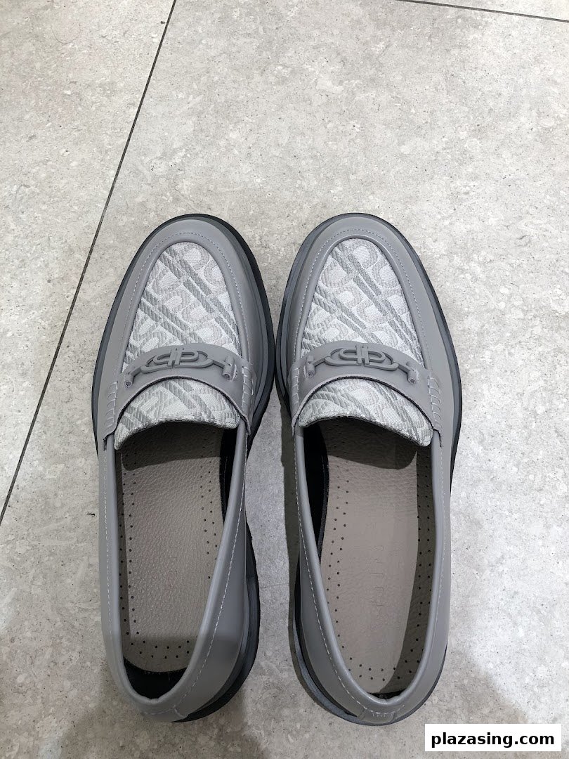 A pair of stylish grey loafers with patterned uppers and metal accents, displayed on a tiled floor.