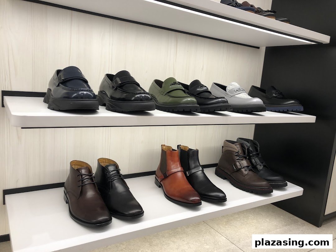 A display of stylish men's shoes and boots on white shelves inside a PEDRO store.