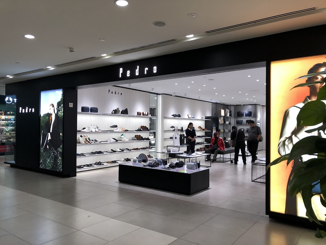 Modern storefront of PEDRO at Plaza Singapura, showcasing footwear and accessories with customers inside.