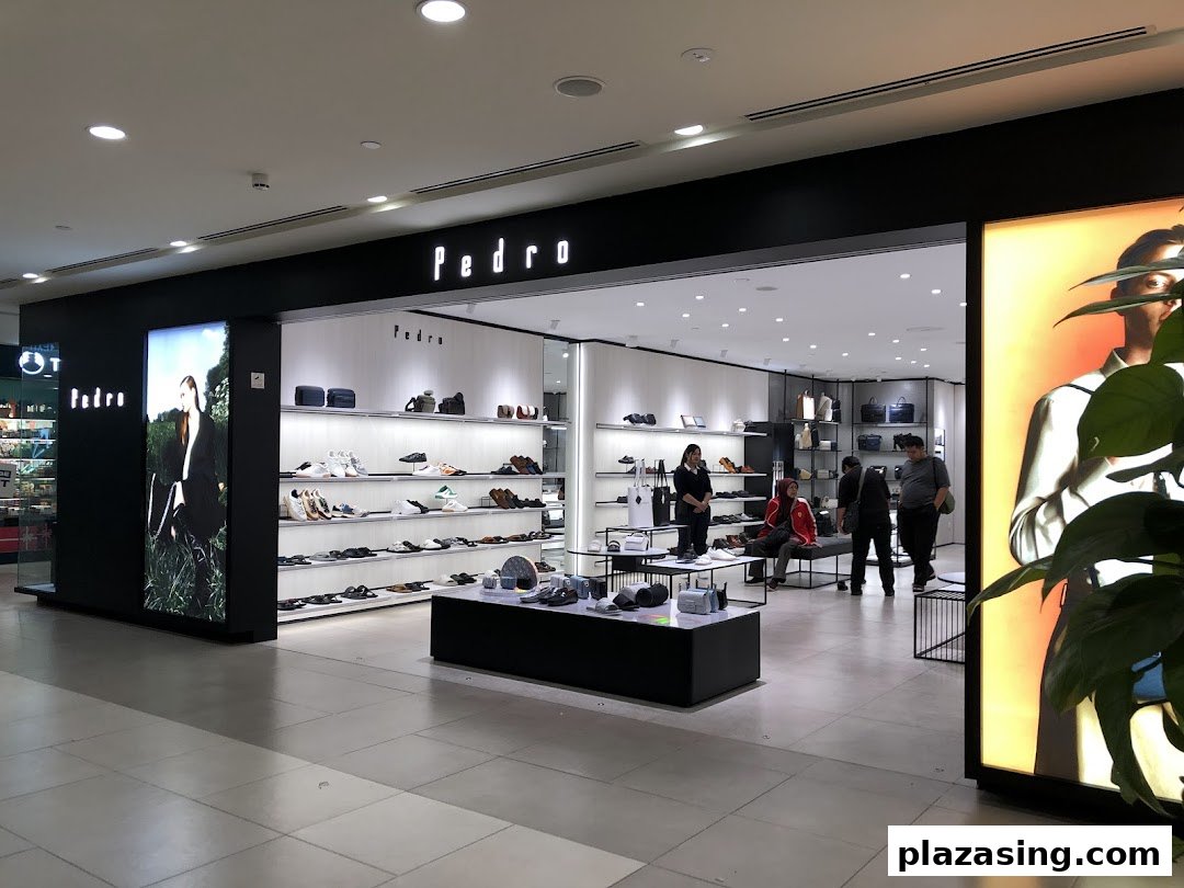 Modern storefront of PEDRO at Plaza Singapura, showcasing footwear and accessories with customers inside.