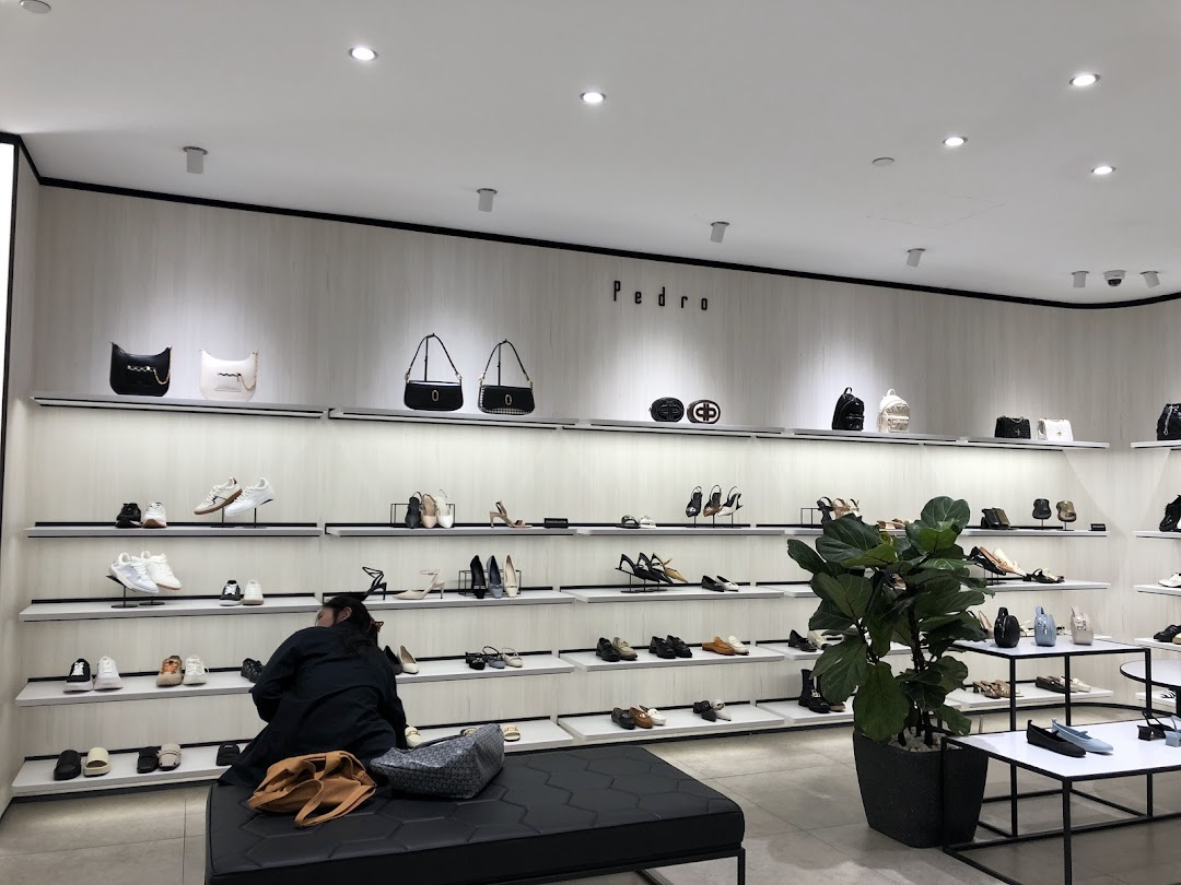 Interior view of PEDRO showcasing a wide array of stylish shoes and bags on display shelves.