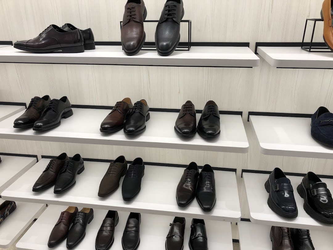 A display of various men's dress shoes and loafers on white shelves inside the PEDRO store.