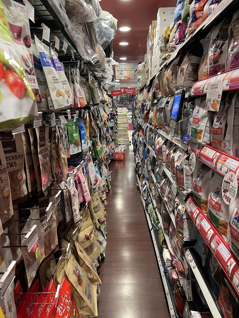 A long aisle in a pet store, fully stocked with various pet food and treat bags.