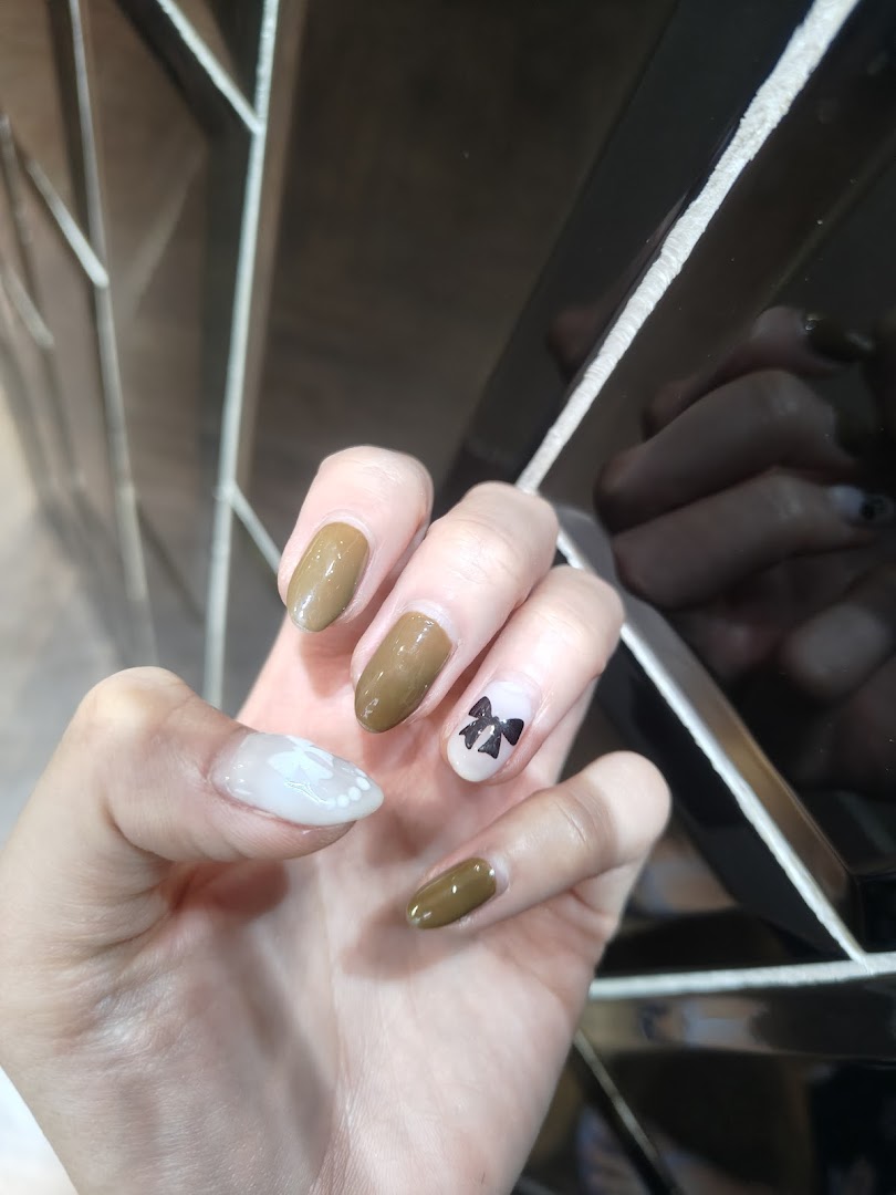 A close-up of a hand showcasing stylish nail art with earthy tones and delicate designs.