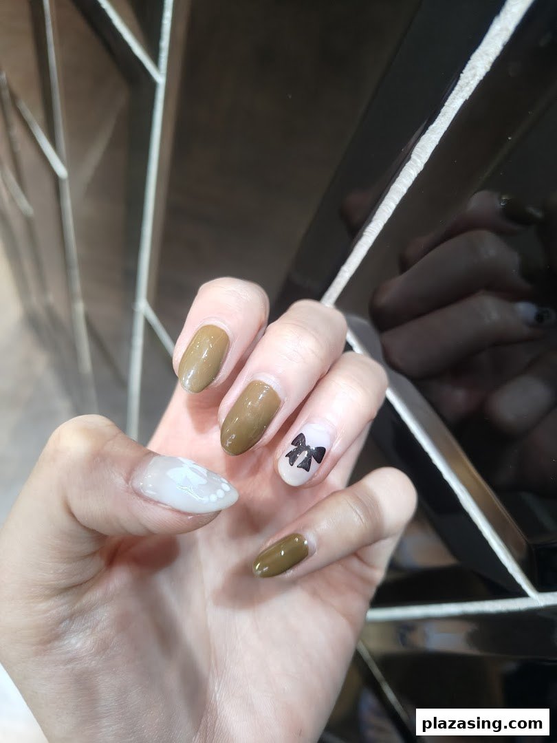 A close-up of a hand showcasing stylish nail art with earthy tones and delicate designs.