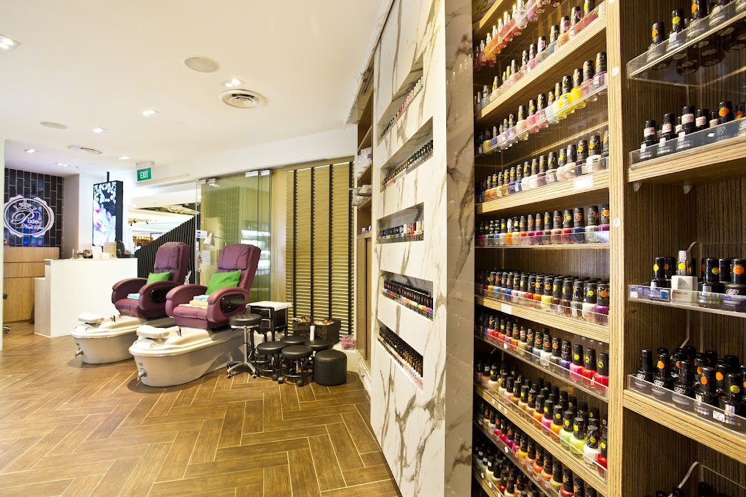 Interior view of a modern nail spa featuring comfortable pedicure stations and extensive nail polish displays.