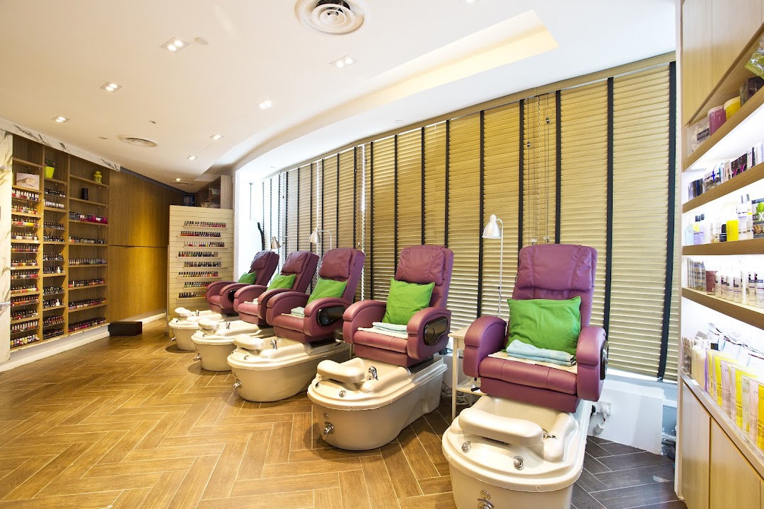 Interior view of a modern nail spa with multiple pedicure chairs and extensive nail polish displays.