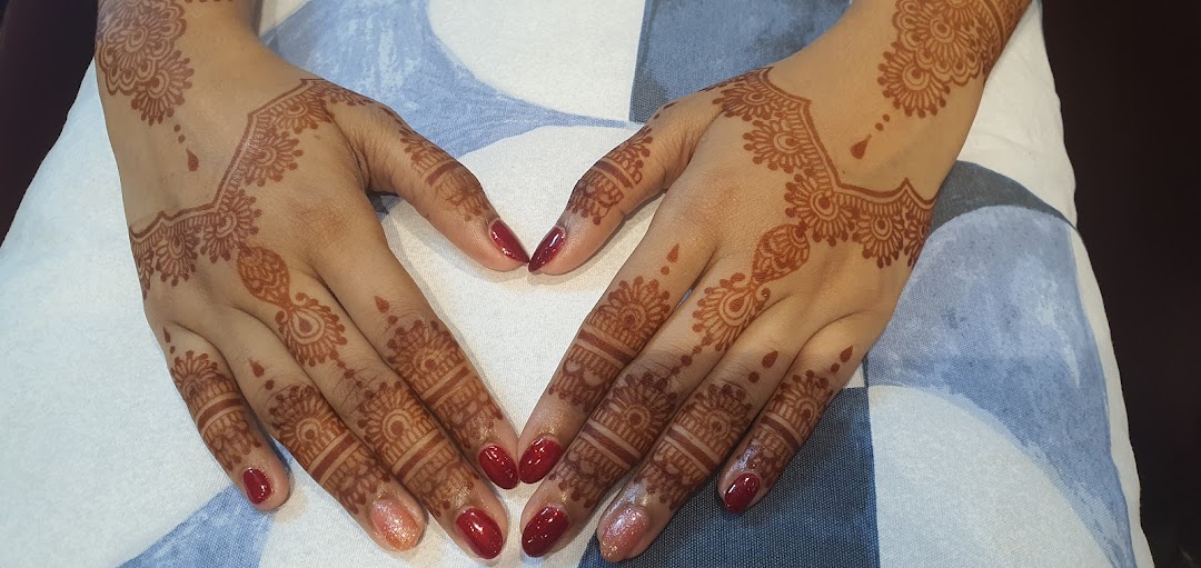Hands adorned with intricate henna designs and vibrant red nail polish, showcasing beauty services.