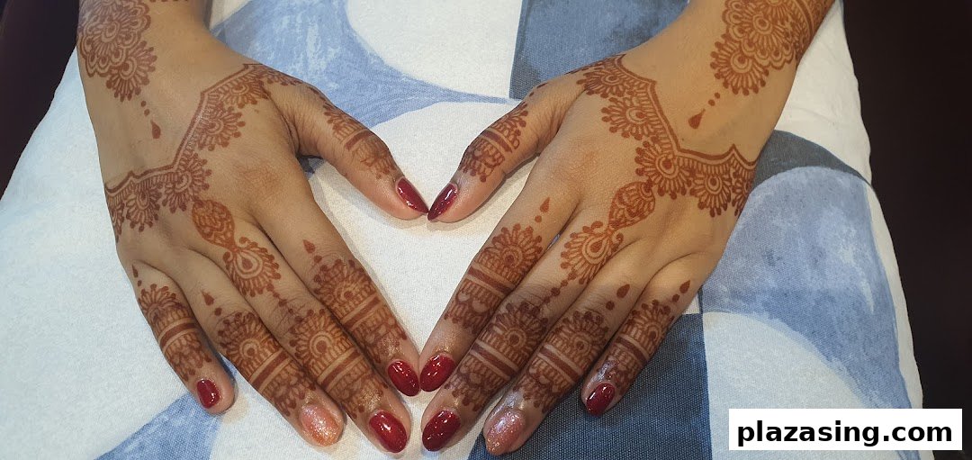 Hands adorned with intricate henna designs and vibrant red nail polish, showcasing beauty services.