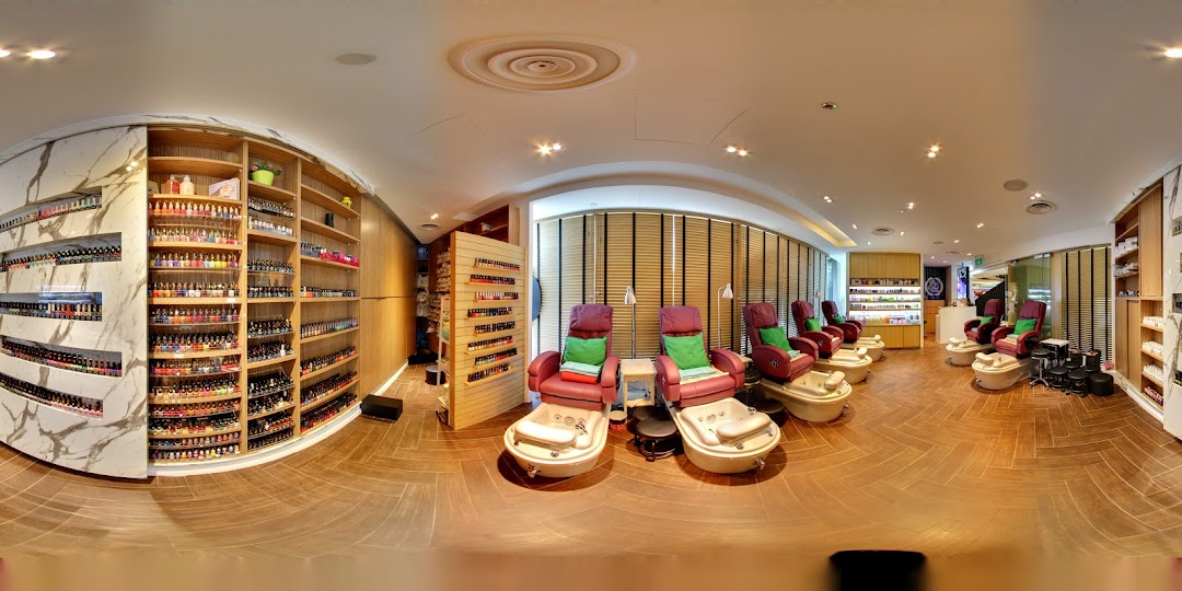 A panoramic view of a modern nail spa interior with multiple pedicure stations and extensive nail polish displays.