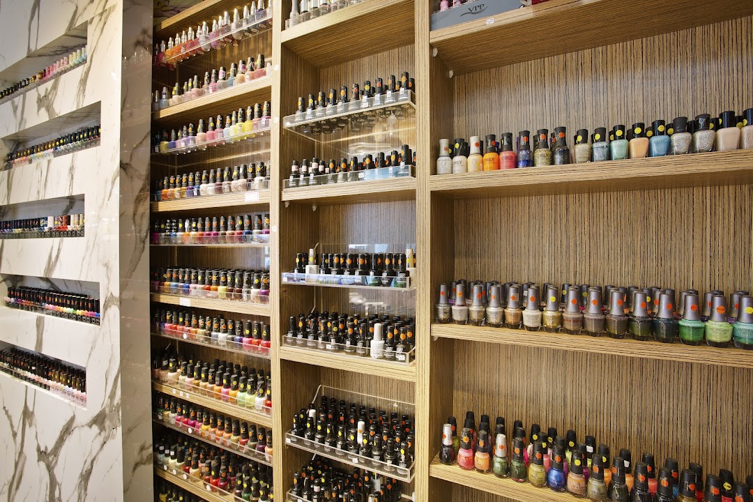Extensive collection of colorful nail polishes displayed on shelves inside a modern nail spa.