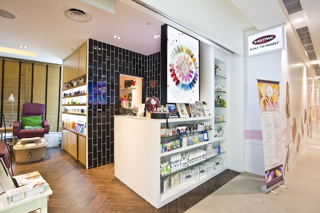 Interior view of a modern nail spa featuring a reception desk, product displays, and a pedicure station.