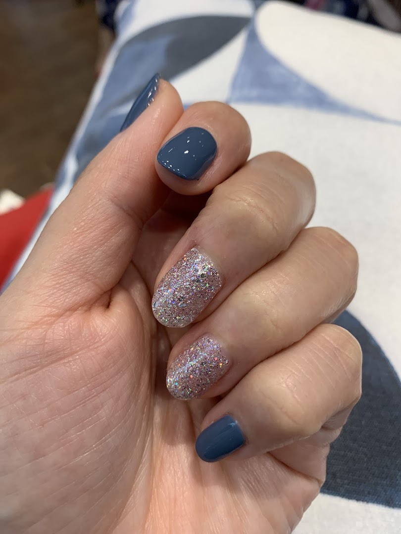 A hand showcasing freshly manicured nails with a mix of solid blue and glitter polish.