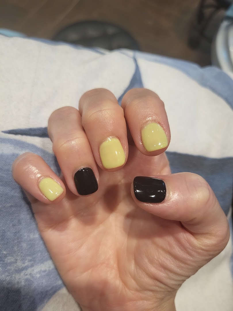 A close-up of a hand showcasing freshly painted nails with alternating black and light yellow polish.