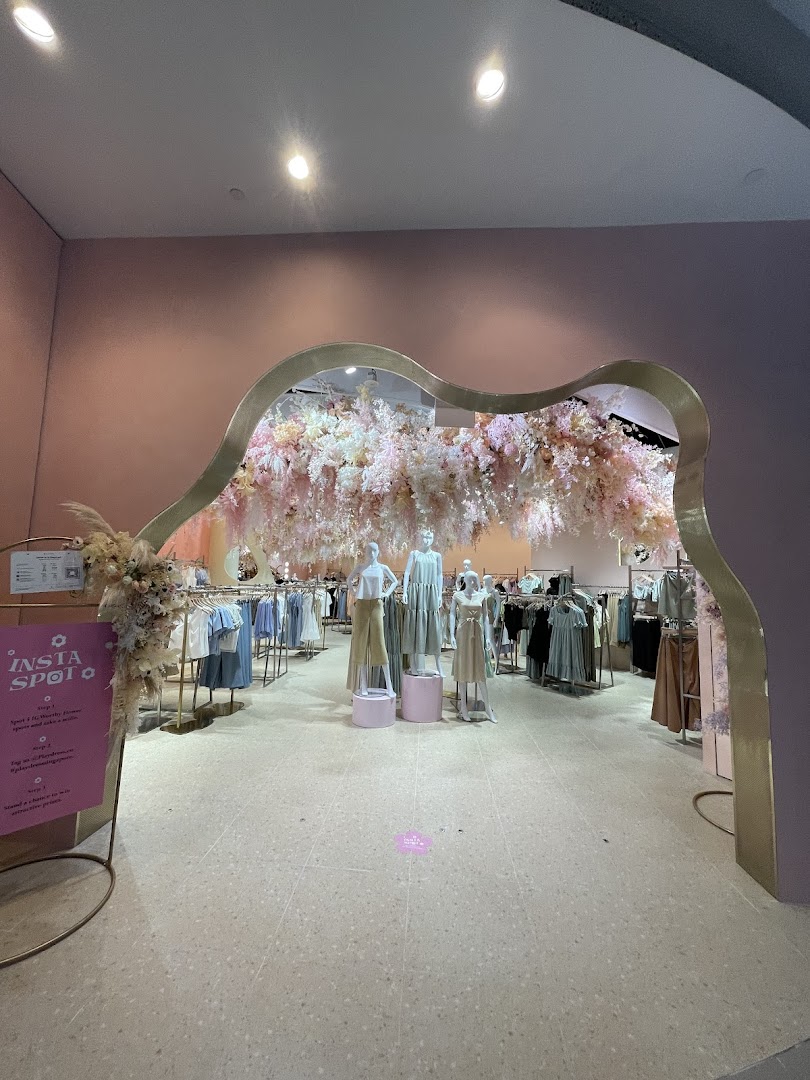 Entrance of Playdress Plaza Singapura with a decorative floral archway and clothing displays.