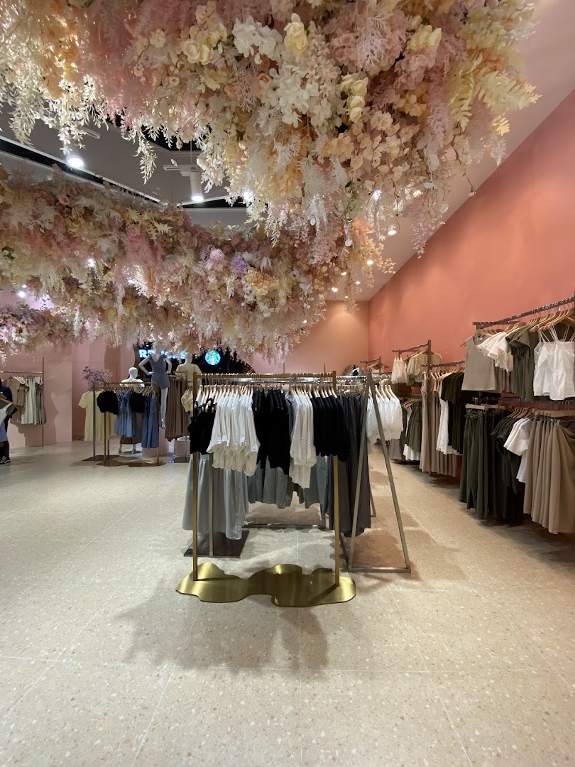 Interior of Playdress Plaza Singapura featuring clothing racks and an elaborate floral ceiling installation.