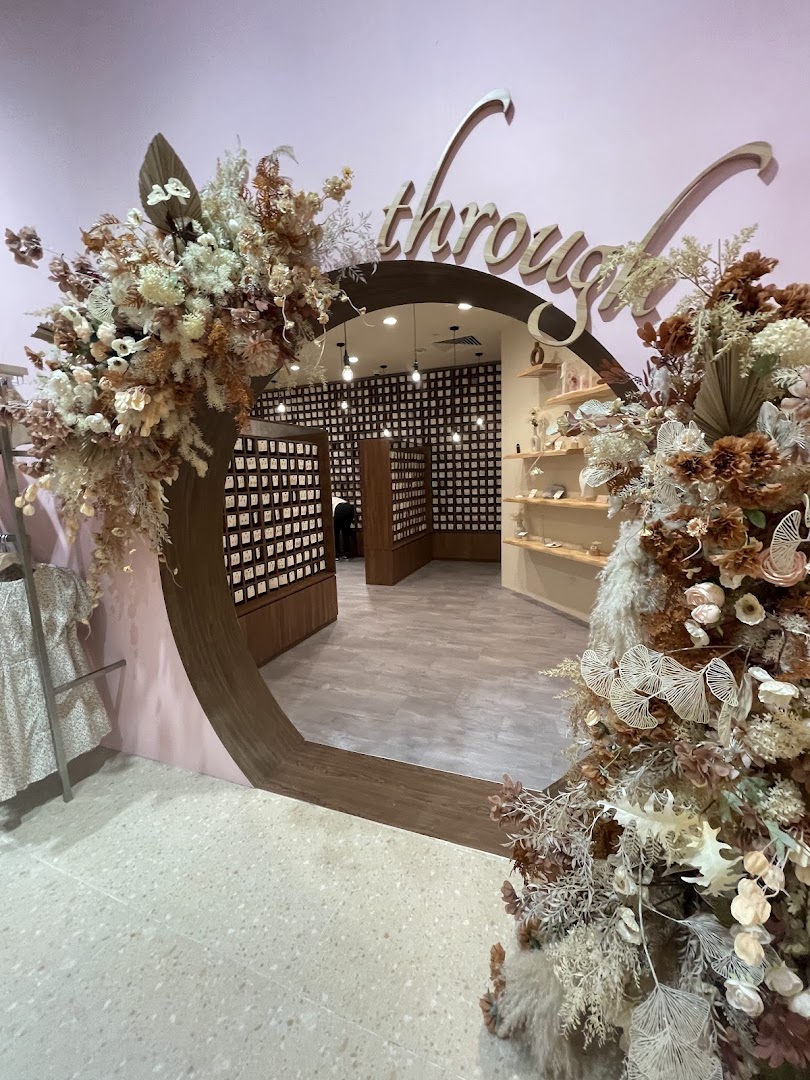An elegant archway entrance to Playdress, adorned with beautiful floral arrangements and foliage.