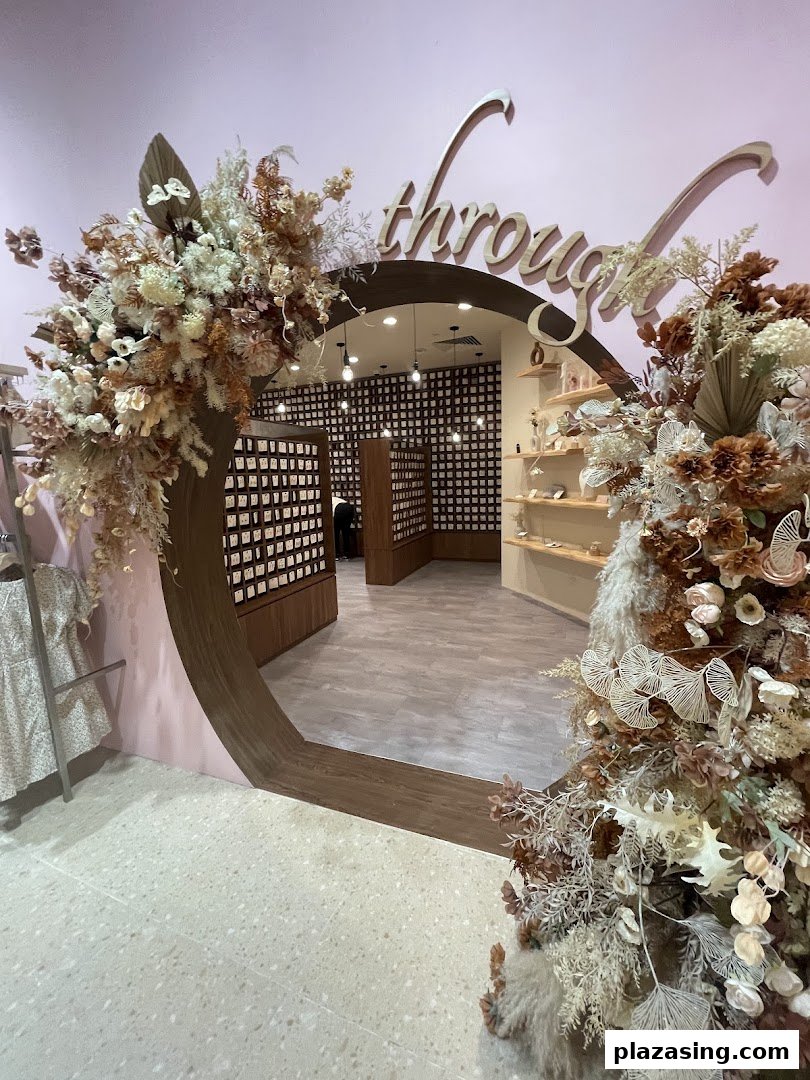 An elegant archway entrance to Playdress, adorned with beautiful floral arrangements and foliage.
