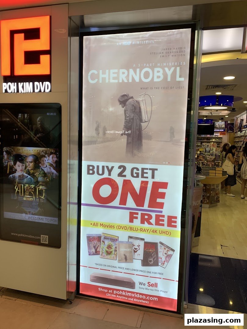 The illuminated storefront of Poh Kim DVD, featuring a large promotional poster for movies and a digital display.