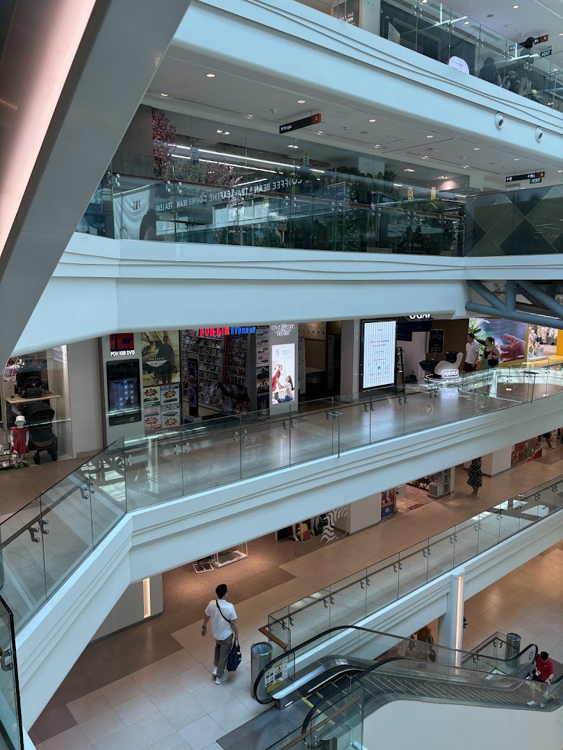 An interior view of a multi-level shopping mall, featuring the Poh Kim shop and escalators.