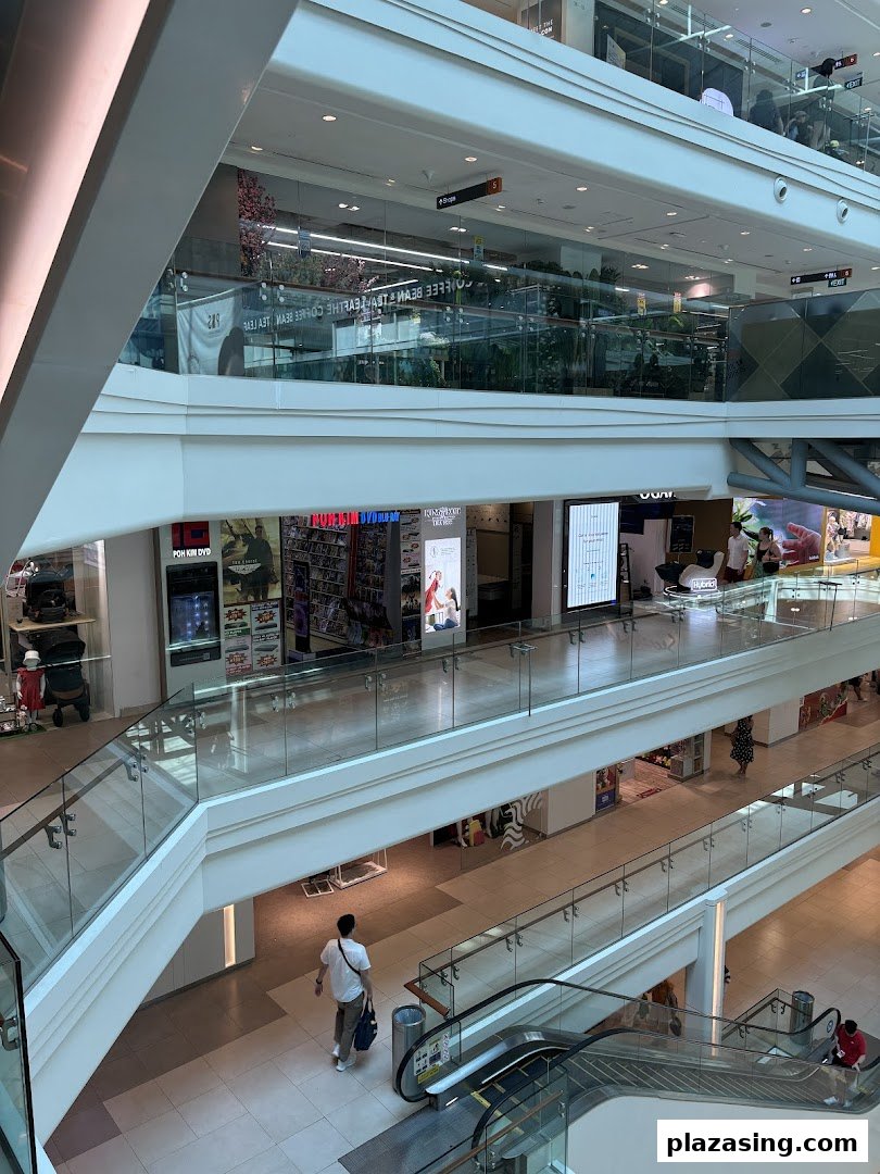 An interior view of a multi-level shopping mall, featuring the Poh Kim shop and escalators.