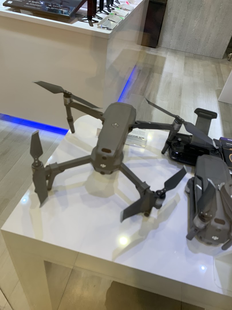 Drones and accessories displayed on a white counter in a tech shop.