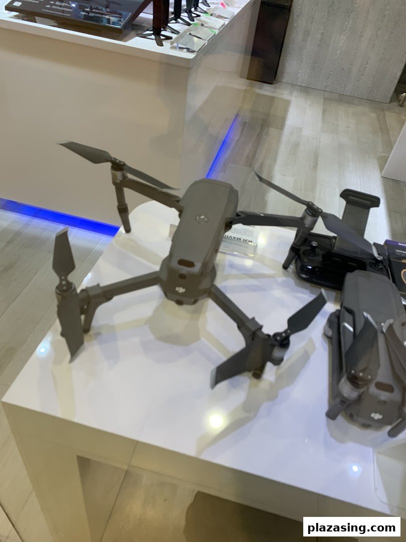 Drones and accessories displayed on a white counter in a tech shop.