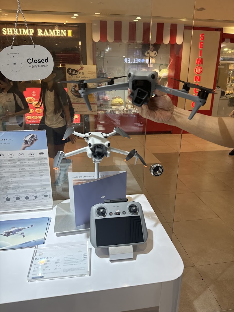 A display inside Propeller Singapore showcasing DJI drones, including the Air 3 and Mini 4 Pro, with a remote controller.