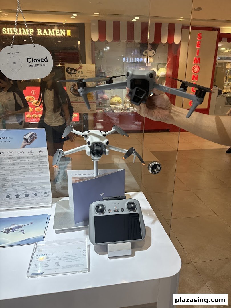 A display inside Propeller Singapore showcasing DJI drones, including the Air 3 and Mini 4 Pro, with a remote controller.