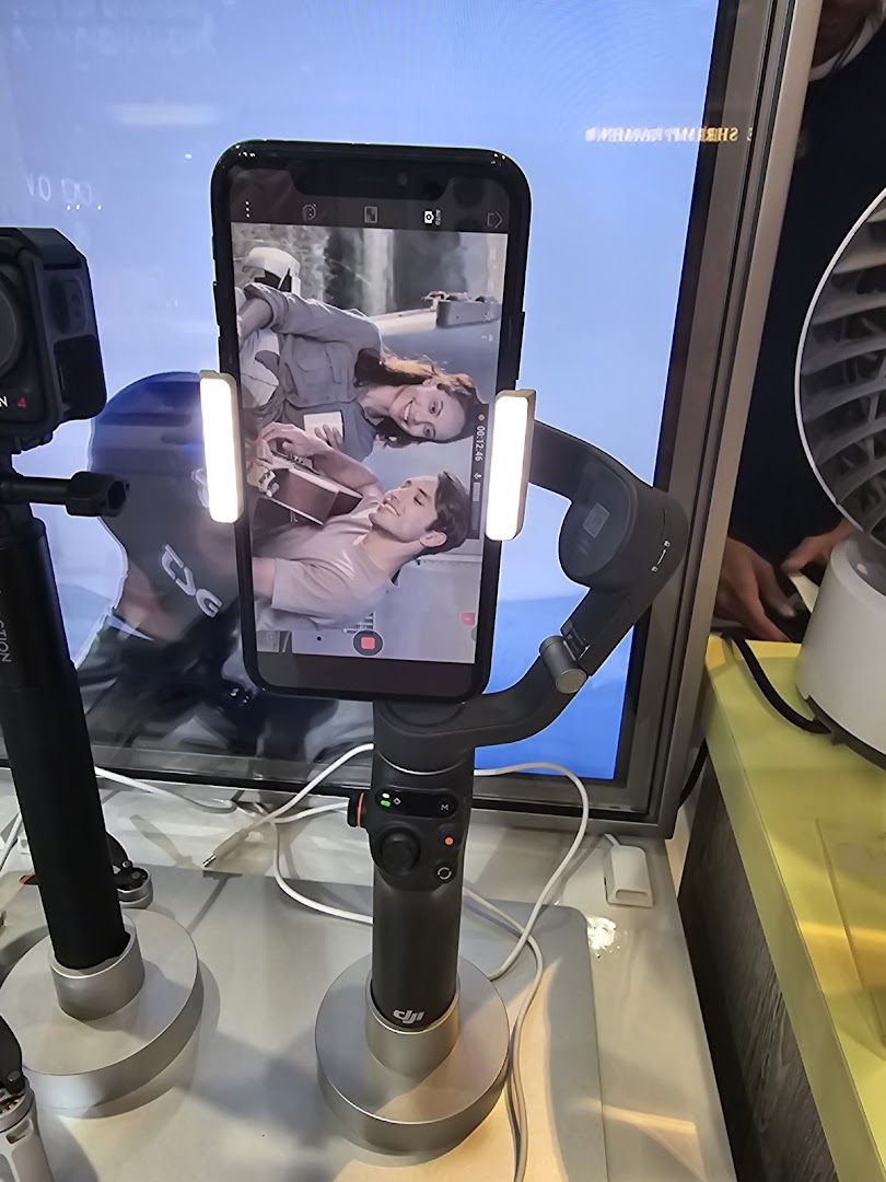A smartphone mounted on a gimbal with attached lights, displaying a video of two people.