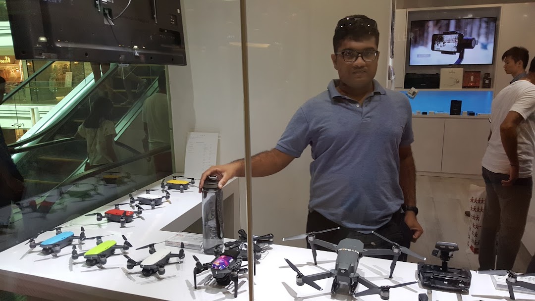A man stands in a tech shop showcasing a variety of drones and camera stabilizers.
