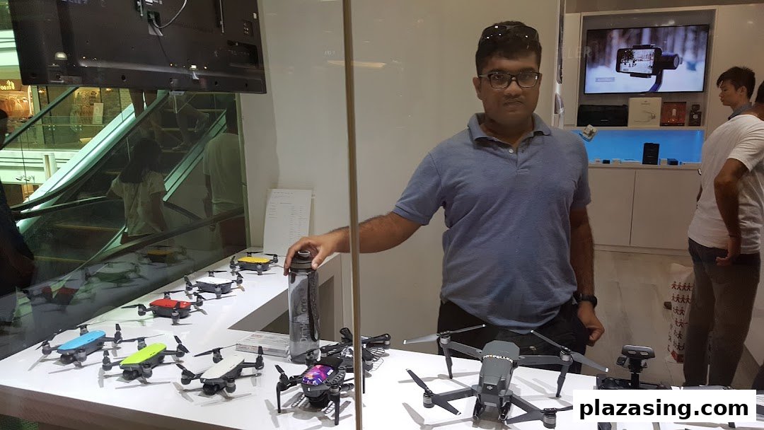 A man stands in a tech shop showcasing a variety of drones and camera stabilizers.