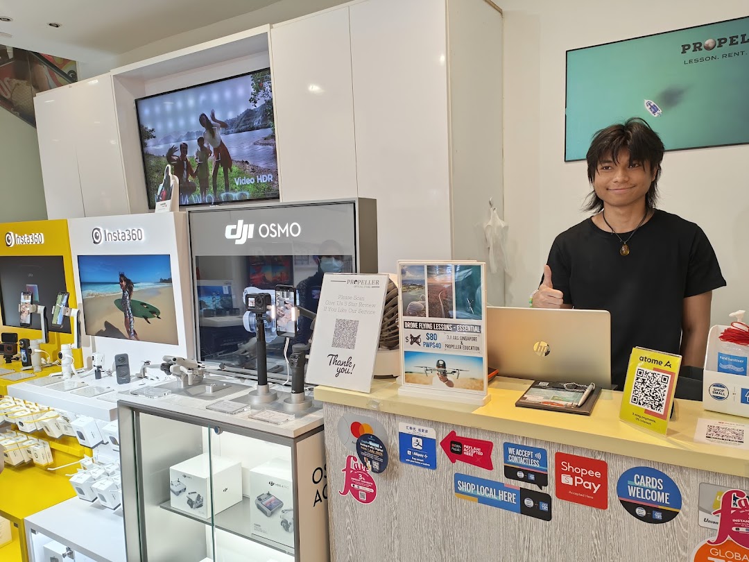 An interior view of Propeller Singapore, showcasing action cameras, drones, and a friendly staff member.