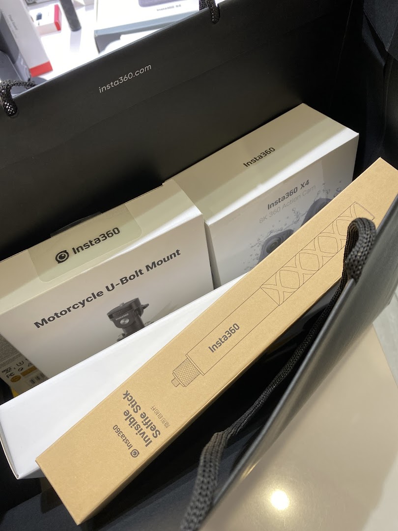 Insta360 action cameras and accessories, including an X4 8K camera and selfie stick, in a shopping bag.